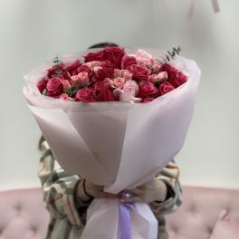 Bouquet of pink and red roses wrapped in pale pink paper
