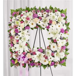Square floral wreath with white lilies, daisies, and pink blooms on an easel