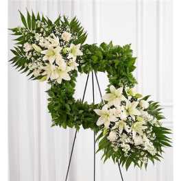 White floral funeral wreath on a black stand