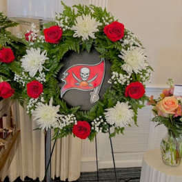 Floral wreath with red roses and white chrysanthemums around a sports logo