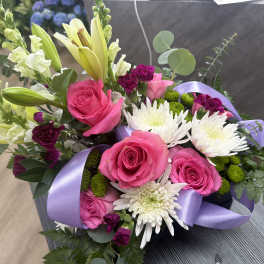 Bouquet of pink roses, white lilies, and white chrysanthemums with a lavender ribbon