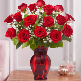Red roses with baby's breath in a red glass vase