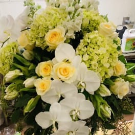 White orchids and pale yellow roses in a silver vase