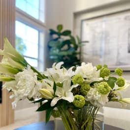 White lilies and green pom-pom flowers in a glass vase