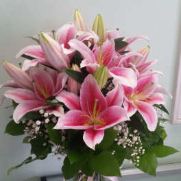 Pink lilies arranged in a clear glass vase with baby's breath