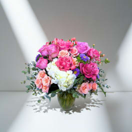 Pink and peach roses with white hydrangeas in a glass vase