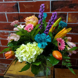 Mixed bouquet with pink daisies, lilies, and hydrangea in a glass vase