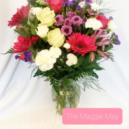 Mixed bouquet of roses, gerbera daisies, and carnations in a glass vase