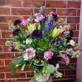 Mixed bouquet of pink, purple, and white flowers in a white vase