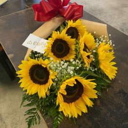 Bouquet of sunflowers wrapped in paper with a large red bow