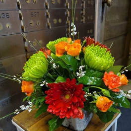 Bright mixed flower arrangement in a small container