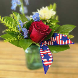 Small bouquet with a red rose, white bloom, and blue flowers in a glass vase