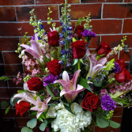 Bouquet of red roses, pink lilies, and white hydrangea in a glass vase