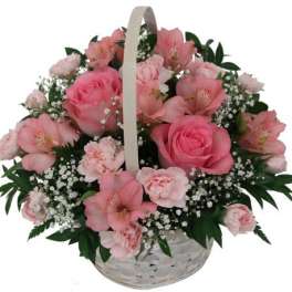 Pink roses and alstroemeria in a white basket with a handle