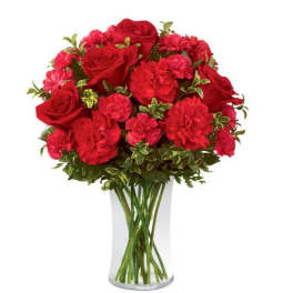 Red roses and carnations in a clear glass vase