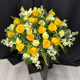 Yellow roses and white lilies in a black pedestal arrangement