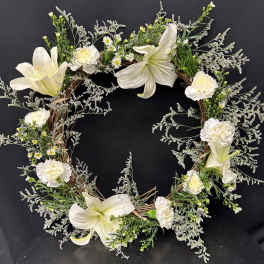 White floral wreath with lilies and carnations on a dark background