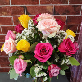 Mixed bouquet of pink, yellow, and white roses in a glass vase