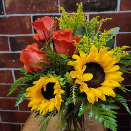 Bouquet of red roses and yellow sunflowers in a glass vase