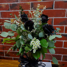 Bouquet of black roses with white filler flowers in a glass vase