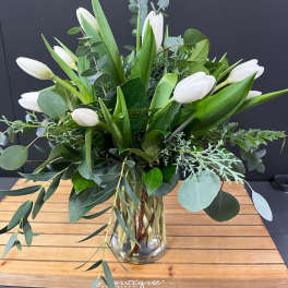 White tulips and eucalyptus in a clear glass vase