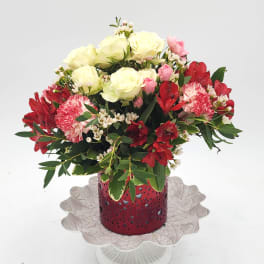 Bouquet of cream and red flowers in a red vase