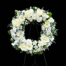 White floral wreath on a black easel stand