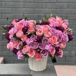 Pink and lavender roses arranged in a white textured vase