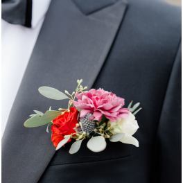 Boutonniere with pink, red, and white flowers on a black suit lapel