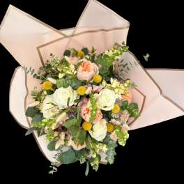 Bouquet of peach and white roses with yellow accents in pale pink wrap