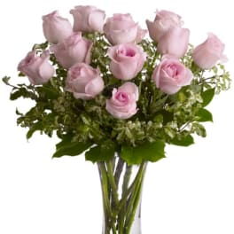 Pink roses arranged in a clear glass vase with greenery