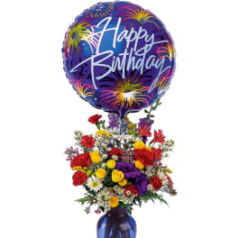 Birthday balloon above a colorful mixed flower arrangement in a blue vase