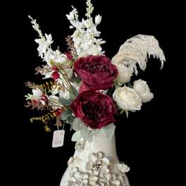 Floral arrangement with burgundy and white blooms in a decorative ceramic vase