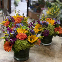 Bright mixed flower arrangements in dark glass vases