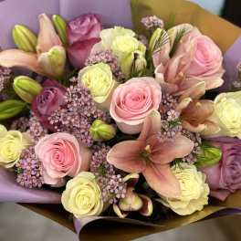 Bouquet of pink and cream roses with lilies wrapped in purple and gold paper