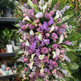 Large standing floral spray with purple roses, white calla lilies, and orchids