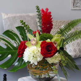 Tropical floral arrangement with red roses and white hydrangeas in a glass vase