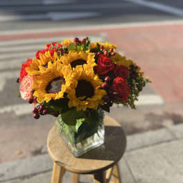 Bouquet of sunflowers and red roses in a glass vase