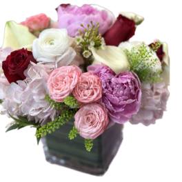 Mixed bouquet of pink, white, and burgundy flowers in a square vase