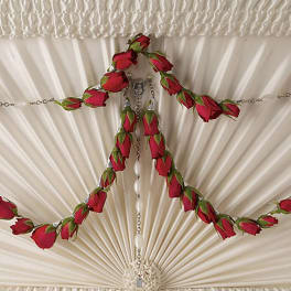 Red rose buds arranged around a hanging cross ornament