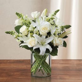 White roses and lilies arranged in a clear glass vase