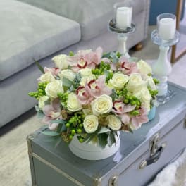 Round bouquet of white roses and pale pink orchids in a white box