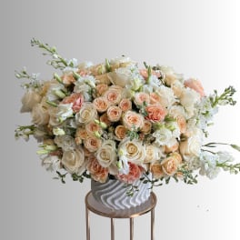 Large bouquet of cream and peach roses in a textured white vase