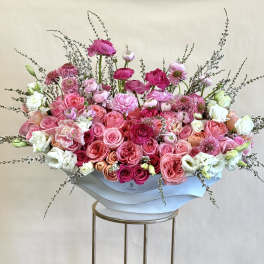 Large pink and white floral arrangement in a white container