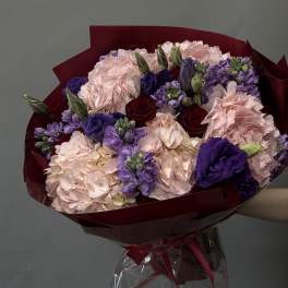 Bouquet of pink, purple, and red flowers wrapped in burgundy paper