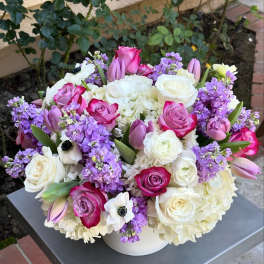 Bouquet of pink and white roses with purple flowers in a white vase