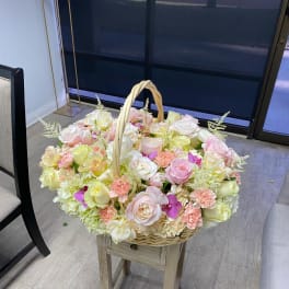 Basket of pastel roses and carnations with small purple accents
