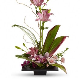 Tall floral arrangement with pink lilies and orchids in a black vase