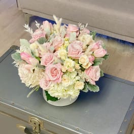 Pink roses and tulips arranged in a white round box