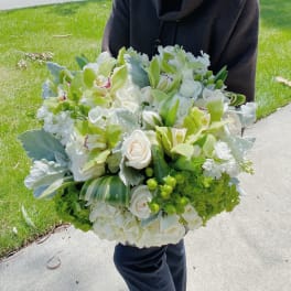Large bouquet of white roses and green orchids held outdoors